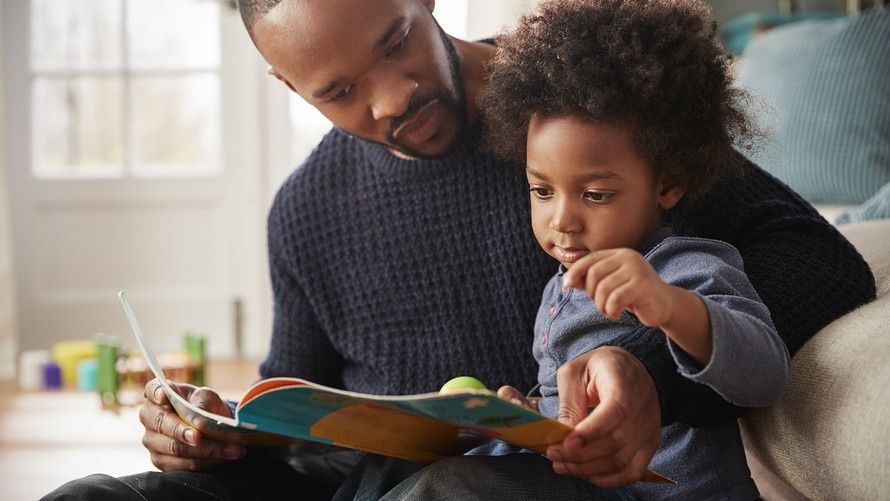 Vader leest samen met een jong kind in een prentenboek